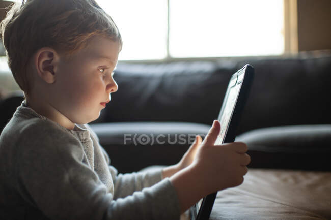 Young boy 3-4 years old watches tablet in the living room at home — Stock Photo
