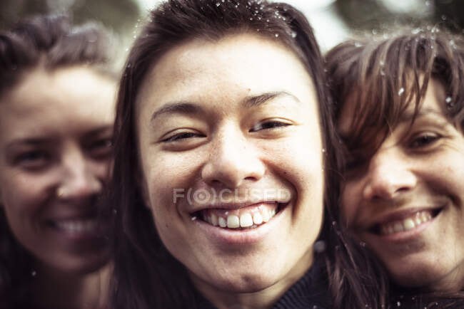 Trois femmes remplissent le cadre de sourires heureux et de neige dans les cheveux en hiver — Photo de stock