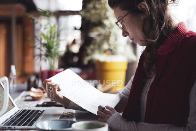Donna d'affari legge scartoffie con computer portatile in ufficio durante covid — Foto stock