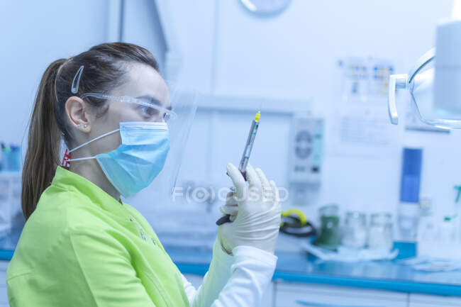 Жінка-стоматолог готує шприц для анестезії в масці — стокове фото