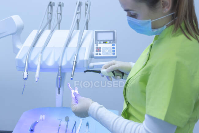Woman dentist with mask using polymerization lamp in dental clinic — Stock Photo