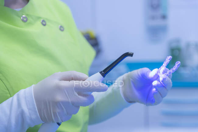 Женские руки дантиста в перчатках с помощью лампы в стоматологической клинике — стоковое фото