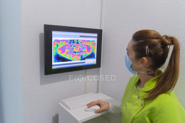 Mulher dentista com máscara analisando uma radiografia na clínica odontológica — Fotografia de Stock