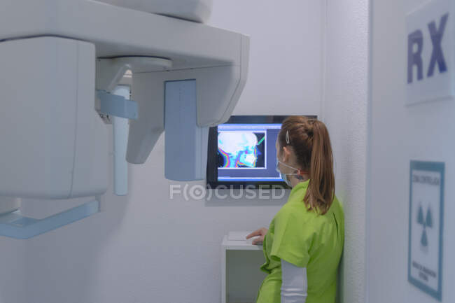 Mulher dentista com máscara verificando uma varredura de raios-x na clínica odontológica — Fotografia de Stock