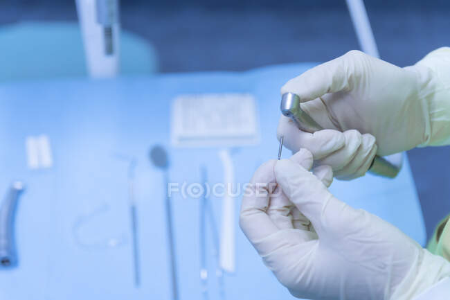 Dentist with gloves on hands preparing the drill in dental clinic — Stock Photo