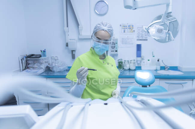 Femme dentiste avec masque facial et écran facial, clinique dentaire — Photo de stock