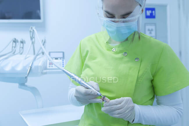 Dentista femenina en ropa protectora haciendo limpieza de prótesis dentales, clínica - foto de stock