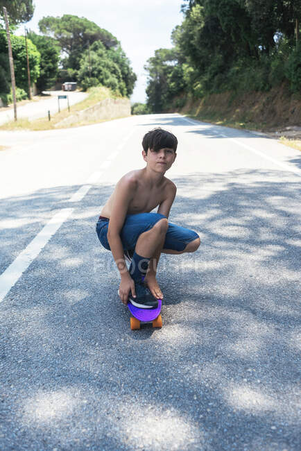 Portrait de joyeux skateboard adolescent torse nu sur route de montagne — Photo de stock