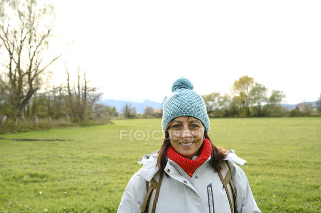 Porträt einer lächelnden Backpacker-Frau mit Wollmütze und Kamera — Stockfoto