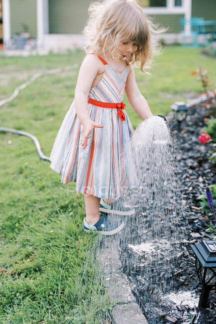 Kleines Mädchen gießt Pflanzen im Hinterhof — Stockfoto