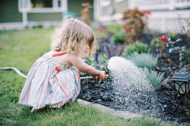 Little girl watering plants  in the backyard — Stock Photo