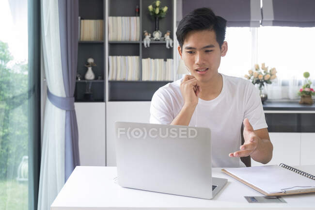 Молодий чоловік працює і вчиться онлайн вдома. Відеоконференція молодої людини онлайн зі своїми колегами . — стокове фото