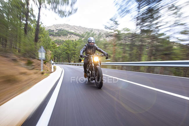 Piloto com moto cuscom preto na estrada ao pôr do sol — Fotografia de Stock