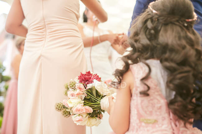 Petite fille tenant bouquet de fleurs à un mariage — Photo de stock