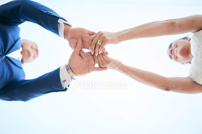 Casal recém-casado de mãos dadas em uma posição de baixo para cima — Fotografia de Stock