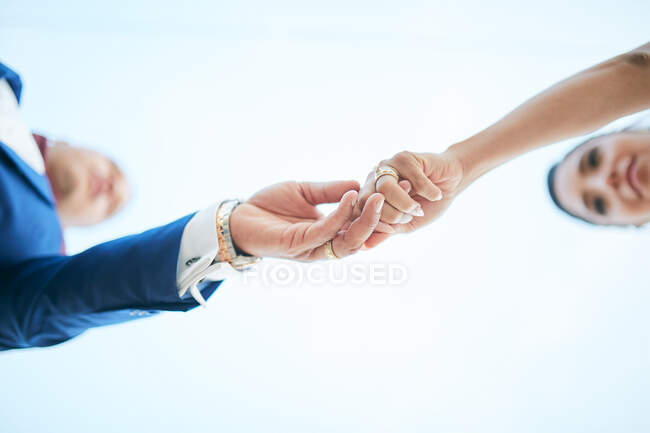 Pareja de recién casados tomados de la mano en una posición ascendente - foto de stock