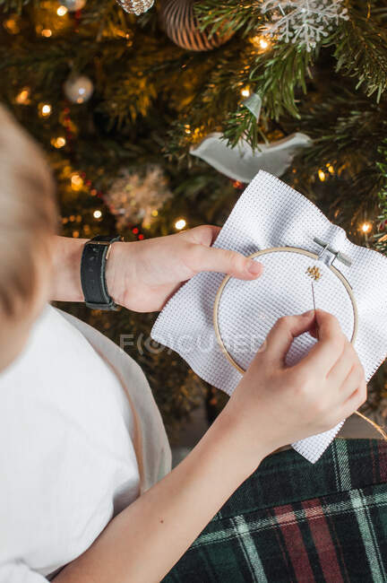 A boy embroidering a picture with a cross on the background of a Chris — Stock Photo