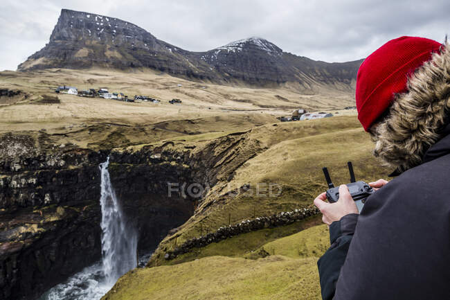 Pilota che vola con il suo drone (uav) sopra la cascata Mulafossur sull'isola di Vagar, nelle isole Faroe — Foto stock