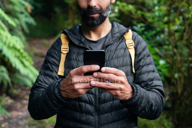Junger Mann benutzt Smartphone-GPS beim Trekking am Berg — Stockfoto