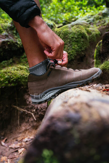 Крупним планом молодий чоловік зв'язує її взуття під час походу — стокове фото