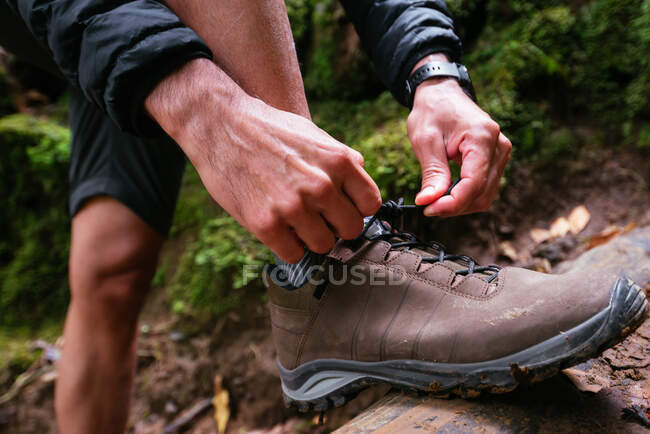 Gros plan jeune homme attacher ses chaussures tout en trekking — Photo de stock