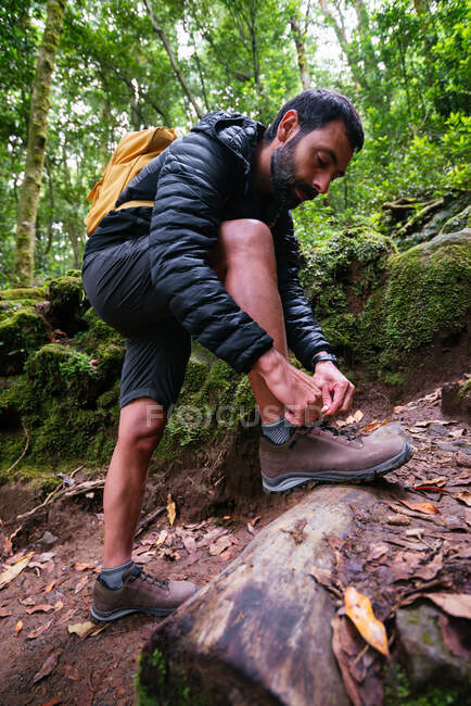 Young man tying her shoes while trekking — Stock Photo
