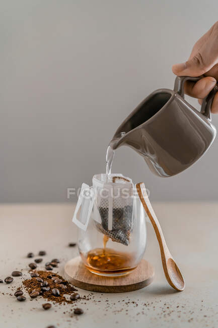 Чай, що вливається в чашку з ложкою на дерев'яному фоні — стокове фото