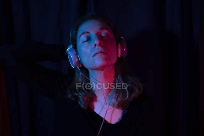 Portrait of woman with headphones set with red and blue neon lights — Stock Photo