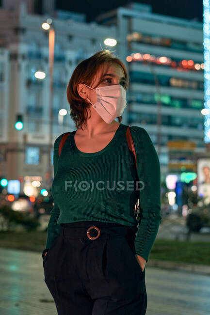 Portrait of a young woman wearing a mask in the city at night — Stock Photo
