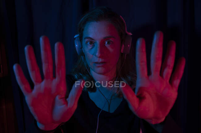 Porträt einer Frau mit Kopfhörern mit roten und blauen Neonlichtern. — Stockfoto