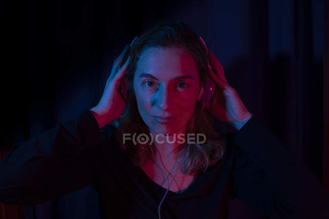 Portrait of woman with headphones set with red and blue neon lights. — Stock Photo