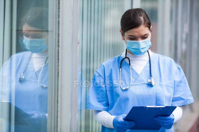 Женщина-врач реанимации проверяет карточку пациента, первая линия реагирования ключевой медицинский работник, скорая помощь во время пандемии коронавируса COVID-19, вне больницы — стоковое фото