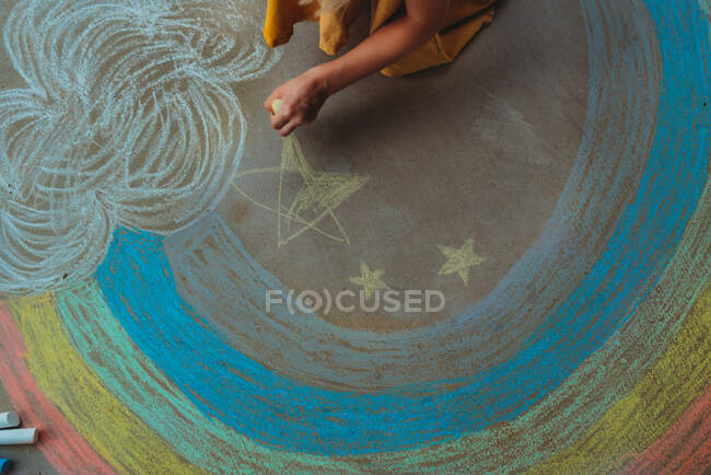 Child with sidewalk chalk and rainbow — Stock Photo