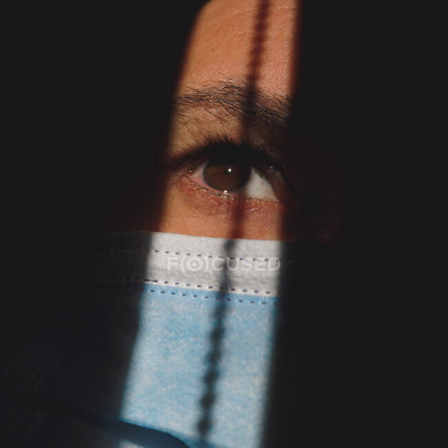 Man with mask in the shadows showing the brown eye — Stock Photo