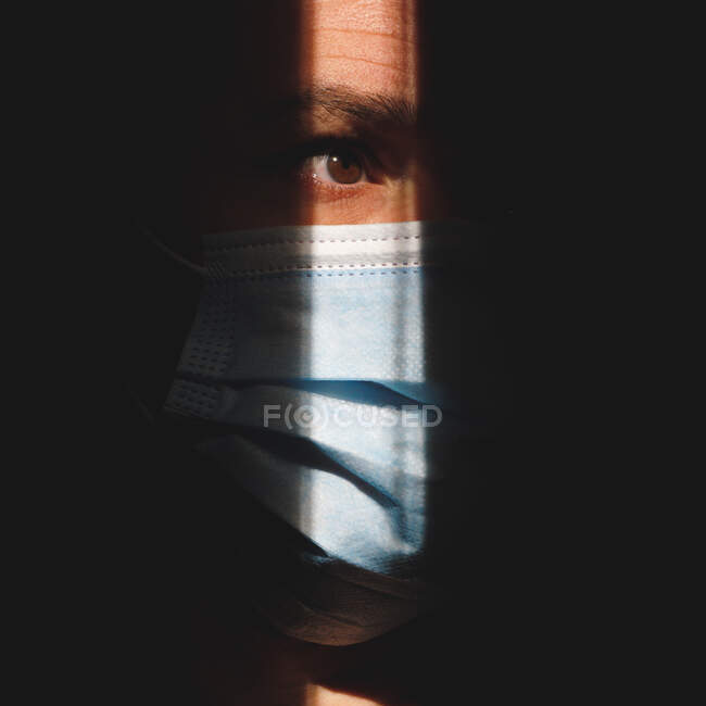 Homme avec masque dans les ombres montrant l'oeil brun — Photo de stock