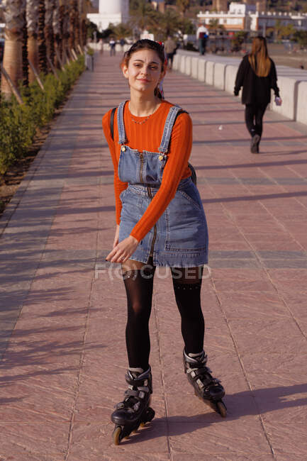 Une jeune femme patine dans les rues de la ville par une journée ensoleillée — Photo de stock