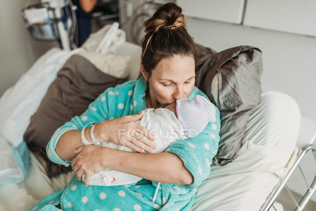 Lifestyle portrait of tired mother kissing newborn son right after birth — Stock Photo