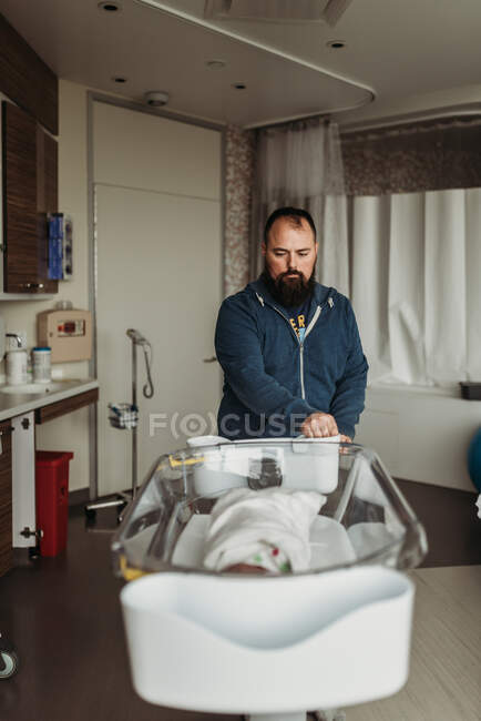 Father moving newborn baby boy's son bassinet in birthing center — Stock Photo