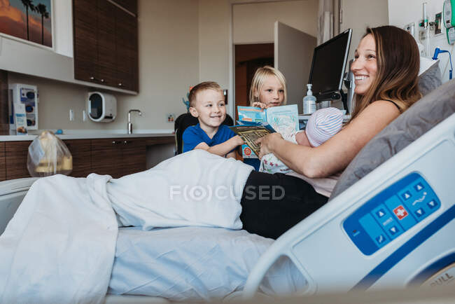 Frères et sœurs rencontrant un nouveau-né frère à l'hôpital pour la première fois — Photo de stock