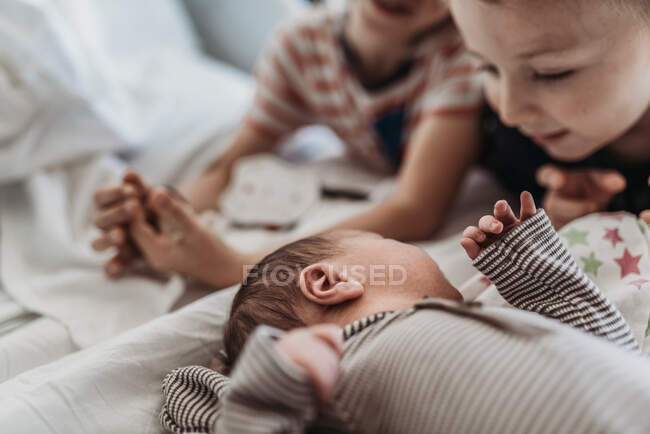 Newborn baby boy meeting big brothers for the first time in hospital — Stock Photo