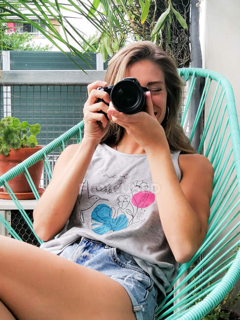 Giovane donna che fotografa su un balcone — Foto stock