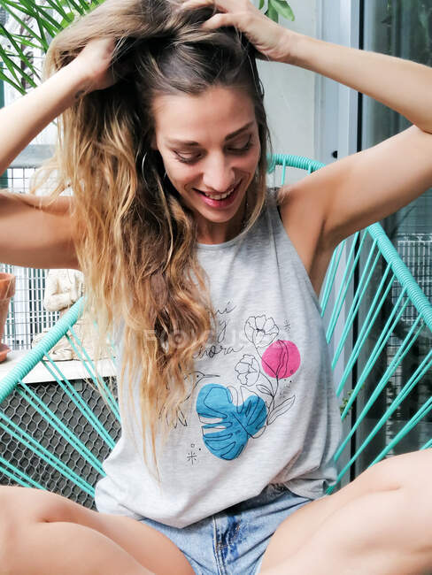 Щаслива жінка грає з волоссям на балконі — стокове фото