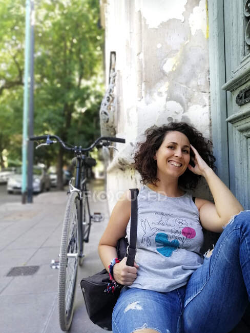 Happy woman while sitting by bicycle — Stock Photo