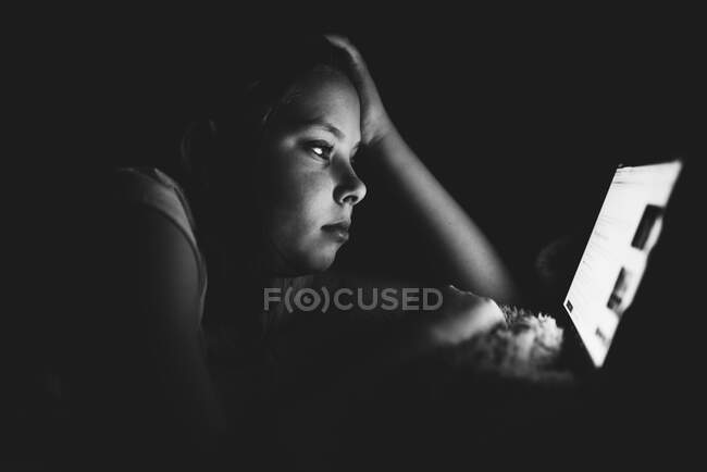 Chica haciendo una búsqueda en línea en una tableta por la noche - foto de stock