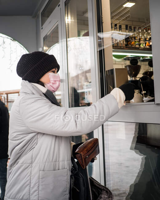 Дівчина в зимовій куртці бере каву — стокове фото