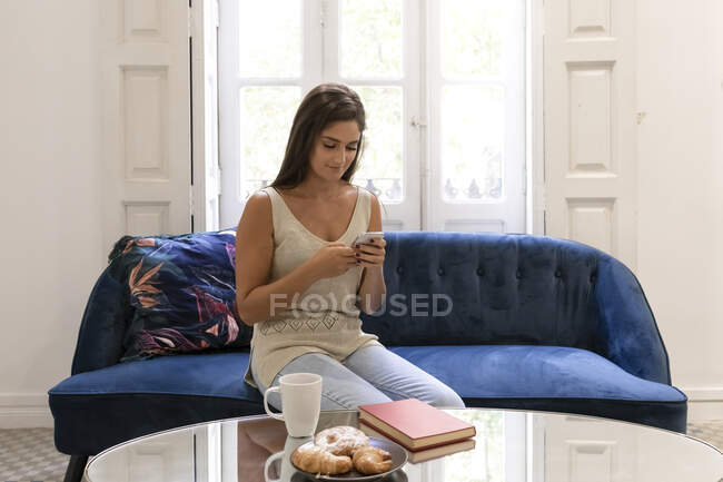 Junge Frau mit Smartphone zu Hause — Stockfoto