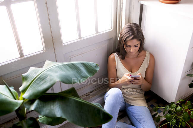 Жінка з мобільним телефоном на кухні — стокове фото
