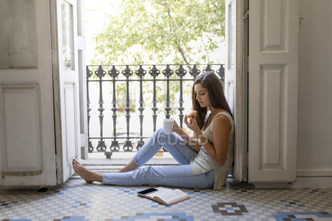 Giovane donna seduta sul pavimento e che legge un libro — Foto stock