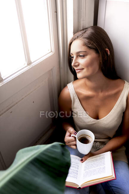 Young woman reading book at home — Stock Photo