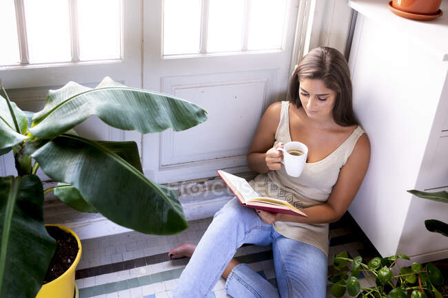 Jovem bela mulher ler livro na sala de estar — Fotografia de Stock